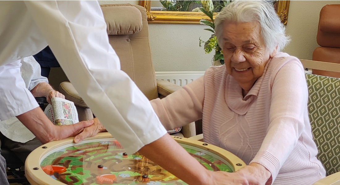 Une femme âgée et son compagnon jouent avec le labyrinthe du Swinging Top.